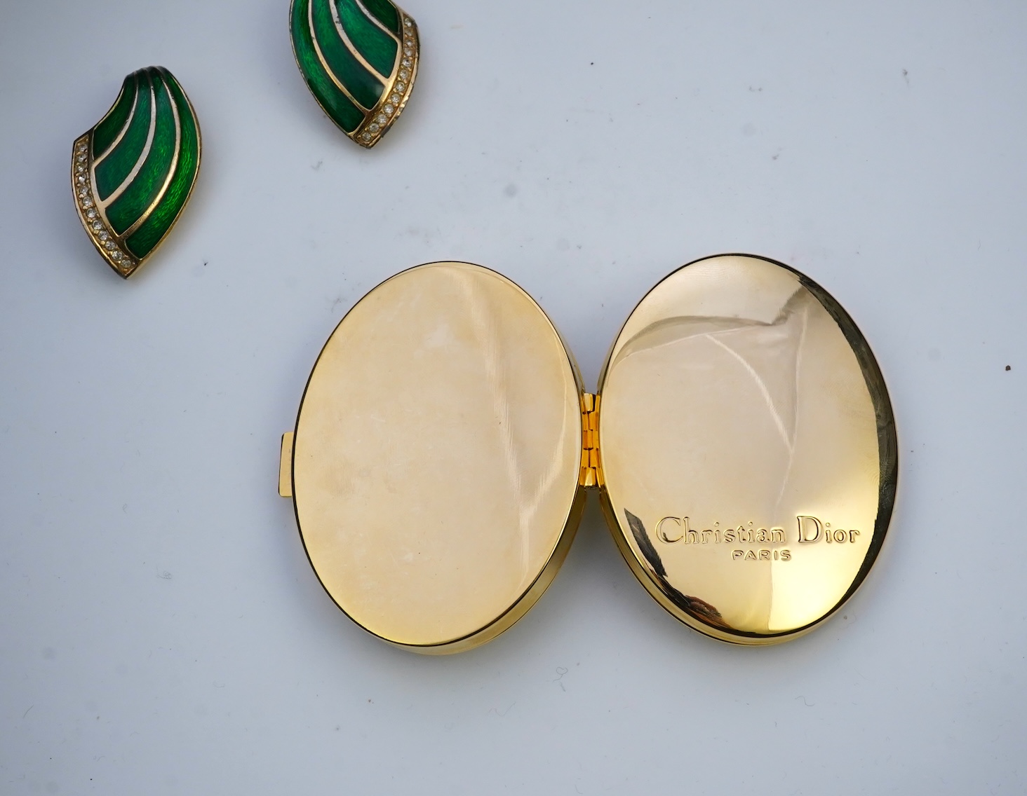 A pair of Christian Dior vintage earrings and compact mirror.